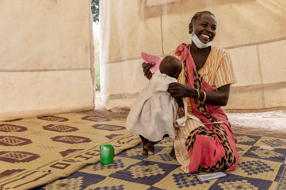 Ateny Mayen Akoi (âge inconnu) tient sa fille Agel, âgée de huit mois, après avoir reçu des médicaments de chimioprévention du paludisme saisonnier (SMC) sur un site de distribution installé dans le village de Kuom, au Sud-Soudan, le 27 octobre 2021. ©Adrienne Surprenant 