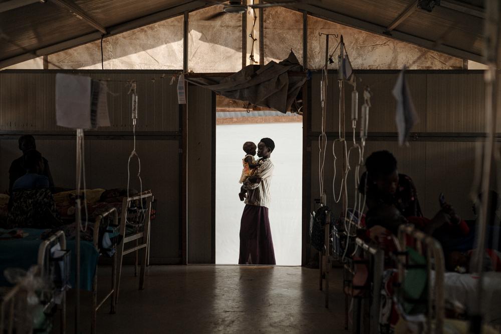 Nyukouth tient dans ses bras sa sœur Nyawan, atteinte d'une pneumonie et d'une forte fièvre, à l'hôpital MSF du camp de Bentiu. Elle se rétablit bien. Sud-Soudan, décembre 2021. © Sean Sutton