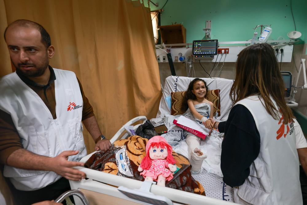 Abdalla Salem (à gauche) est un psychologue de MSF à l'hôpital Al Aqsa. Razan Samer Shabet, la jeune fille, a perdu toute sa famille dans le bombardement alors qu'elle était blessée. Depuis, elle est à l'hôpital. Un oncle éloigné s'occupe d'elle. Elle ne sait pas que sa famille a été tuée. © Mohammed ABED