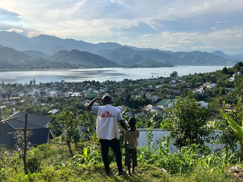 Un membre du personnel de MSF et un enfant observent la ville de Minova et le lac Kivu depuis le sommet d'une colline. Province du Sud-Kivu, est de la RDC. © Igor Barbero/MSF