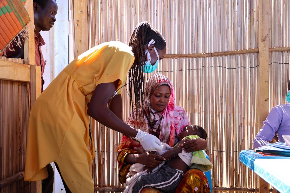 Halima Abdurahman Dawud tient dans ses bras sa fille Aszed Mohammed, qui reçoit un vaccin sur le site de distribution de Renk, dans le Haut-Nil. Halima est une réfugiée soudanaise qui est venue chercher la sécurité à Renk. Elle a acheté sa fille pour les vacances sur le site MSF du centre de transit. © MSF