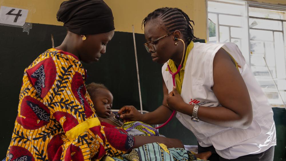 Le Dr Beauty soigne Firdausi, atteinte d'un paludisme sévère, dans les locaux de MSF à l'hôpital général de Shinkafi, tandis que sa mère Basira Sirajo la tient dans ses bras. État de Zamfara, Nigeria, octobre 2023. ©MSF/ABBA ADAMU MUSA