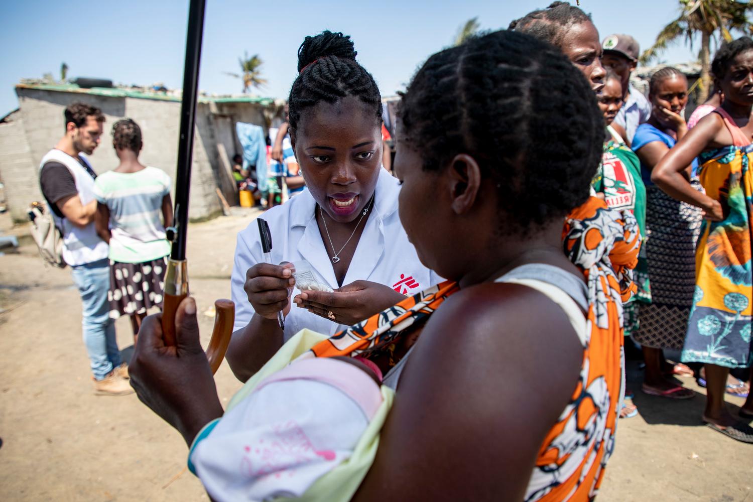 Une infirmière donne des médicaments à une femme portant son enfant dans ses bras, devant l&#039;une des cliniques mobiles de MSF à Beira, une zone très touchée par le cyclone Idai. Mozambique. Mars 2019. 