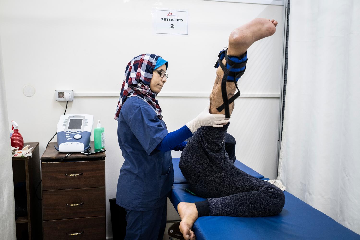 A physiotherapist working with MSF at Al Awda hospital in northern Gaza, assists a patient with his exercises. Palestine, November 2019. 