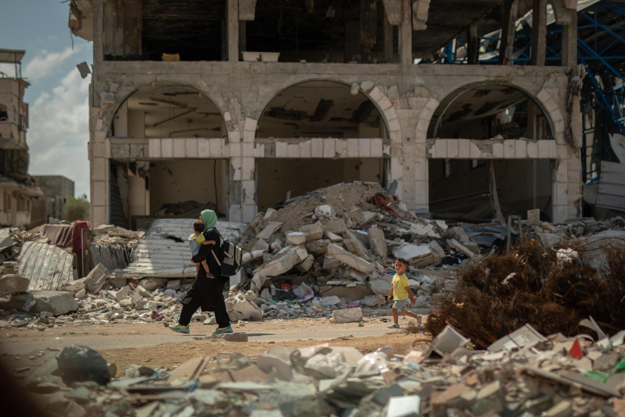 Dans le quartier de Shujaeyya, rue Bagdad, à Gaza, une femme ramène son enfant à la maison à travers les décombres. Septembre, 2024 ©Motassem Abu Aser| MSF