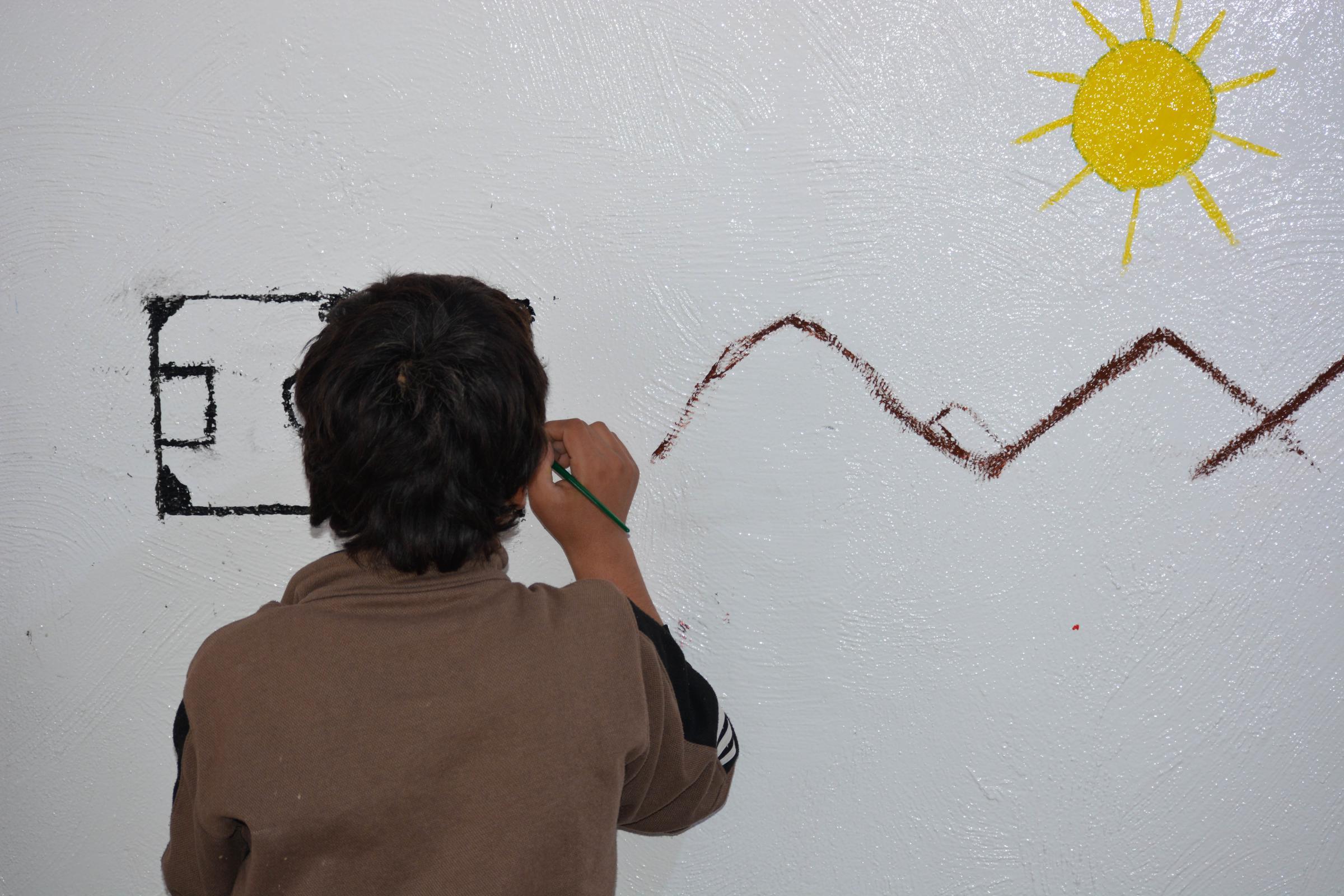 Un adolescent dessine sur le mur de la clinique de santé mentale de MSF au camp d'Al-Hol, dans le nord-est de la Syrie